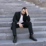 Businessman in a suit sitting distressed on concrete stairs, facing challenges.